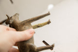 Detail of a vintage ram sculpture's leg showing its rough handmade texture and aged green patina.