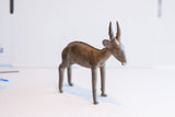 Side profile of a vintage African antelope sculpture highlighting its textured, aged finish.