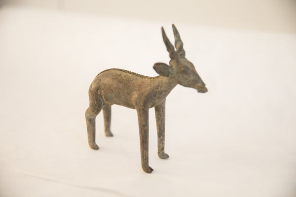 A vintage African antelope sculpture shown in profile, with a textured, aged finish.