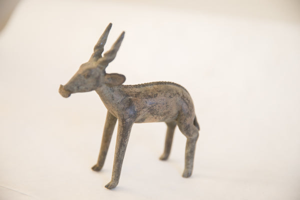 Side profile of the handmade vintage African antelope sculpture highlighting its rustic patina.