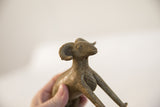 Profile view of the vintage ram sculpture, highlighting its curved horns and textured finish.