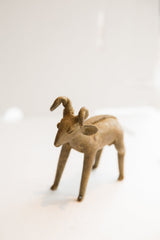 Side profile of a handmade African ram sculpture showing its rustic texture.