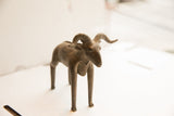 Vintage ram sculpture from an angle, showcasing its curved horns and textured body.