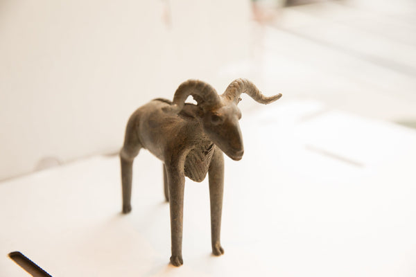 Vintage ram sculpture from an angle, showcasing its curved horns and textured body.