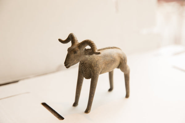 Angled view of the vintage African ram sculpture highlighting its rustic, handmade form.