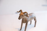 Angled view of the ram sculpture's head, showing its aged handmade texture and horns.