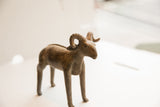 Side profile of the vintage African ram collectible with a textured patina.