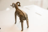Vintage ram sculpture viewed from behind, showing its textured spine and horns.