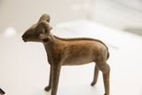 Side view of the vintage ram sculpture highlighting its textured body and braided spine detail.