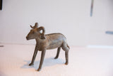 Three-quarter view of a vintage ram sculpture with detailed curved horns and a dark, aged finish.