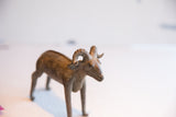 Three-quarter view of the vintage African ram sculpture, showing its full form and aged texture.