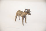 Three-quarter view of a vintage African ram sculpture showing its aged patina.