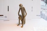 Three-quarter view of the vintage African monkey sculpture showing the smaller figure at its side.