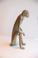 Side profile of the slender, vintage African monkey sculpture in a seated pose.