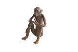 Vintage African sitting monkey with banana sculpture showing a dark, rustic patina.