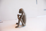 Side profile of the vintage sitting monkey sculpture highlighting its rustic, handmade form.