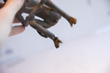 Underside view of the handmade monkey sculpture, showing the aged texture of its legs and feet.