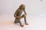 Side view of the sitting monkey sculpture showing its handmade form and texture.