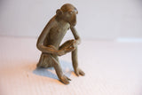 Three-quarters view of the vintage monkey sculpture highlighting its rustic, handmade texture.