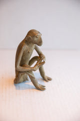 Side profile of a vintage monkey sculpture showing its slender build and aged, textured surface.