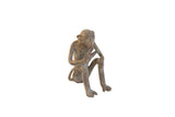 Vintage handmade African monkey figurine with a weathered patina, seated and eating a banana.