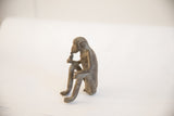 Side profile of the seated vintage African monkey figurine showing its handmade texture.