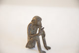 Vintage monkey figurine in profile, showing aged texture and handmade details.