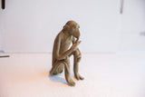 A vintage African monkey figurine sits in profile, highlighting its unique handmade form.