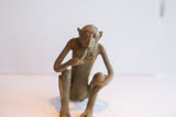 Frontal view of a vintage African monkey figurine in a seated, thoughtful pose.