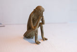 Profile view of the handmade African monkey figurine in a thoughtful pose.