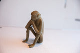 Side profile of the vintage monkey figurine in its contemplative, seated posture.