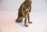 Side view of the vintage monkey figurine in a contemplative, seated pose.