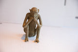 Three-quarter view of the pensive, sitting vintage African monkey sculpture.