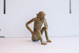 Vintage African monkey figurine in a pensive pose, shown from a three-quarter angle.