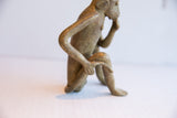 Profile view showing the handmade form and thoughtful pose of a vintage monkey figurine.