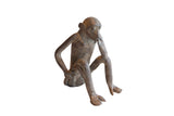 Vintage handmade African monkey figurine in a thoughtful pose with a rustic dark patina.