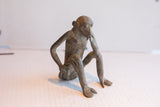 Vintage African monkey figurine shown from the side in a pensive, seated pose.
