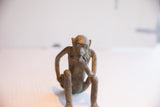 Close-up on the vintage African monkey figurine's aged face and pensive posture.