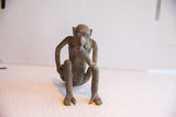 Handmade monkey figurine with a textured patina, shown front-on in a pensive pose.