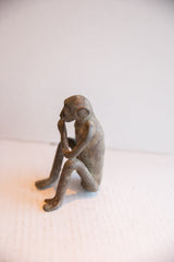 Profile view of the vintage sitting monkey figurine in a thoughtful, pensive pose.