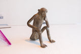 Side view of the vintage African monkey figurine highlighting its thoughtful pose and aged texture.