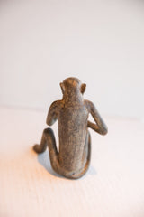 The back of the vintage sitting monkey figurine, showing its slender form and textured patina.