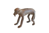 Vintage handmade African figurine of a monkey with a textured spine eating a banana.