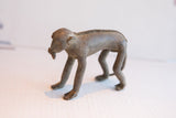 Vintage African monkey figurine in profile, showing its long body and textured spine.