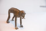 The elongated body and rustic surface of the handmade African monkey figurine.