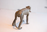 Rear view of vintage monkey figurine highlighting the etched spine and long tail.