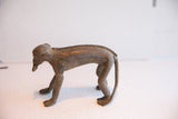 Vintage monkey figurine in profile showing aged patina and braided spine detail.
