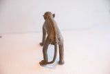 Back view of vintage monkey figurine highlighting the raised, textured spine and curled tail.