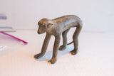 Three-quarter profile of a handmade African monkey sculpture with a rustic, dark patina.