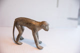 Profile view of the vintage African monkey figurine highlighting its braided spine and weathered texture.